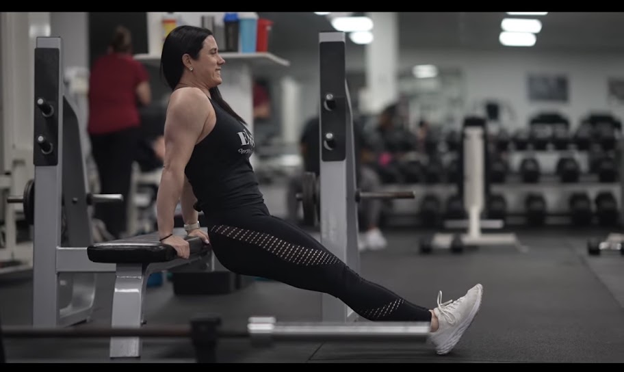 Female fitness coach Jennifer Schulze helping a woman perform strength training exercises, demonstrating the importance of building muscle and confidence after 40.